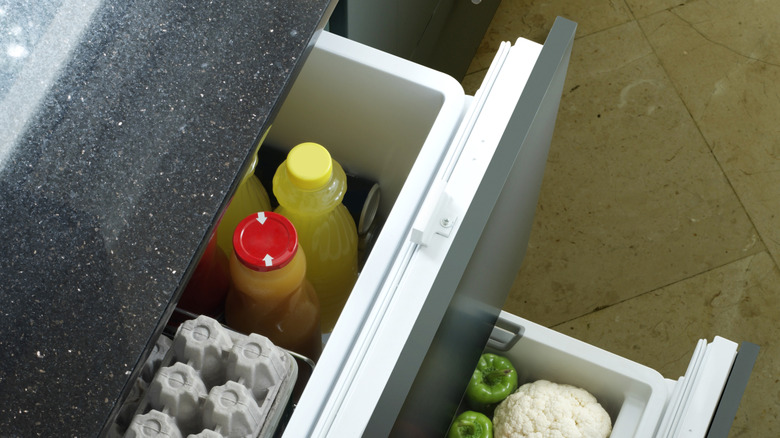Gray under counter drawer refrigerators stocked with produce and juice