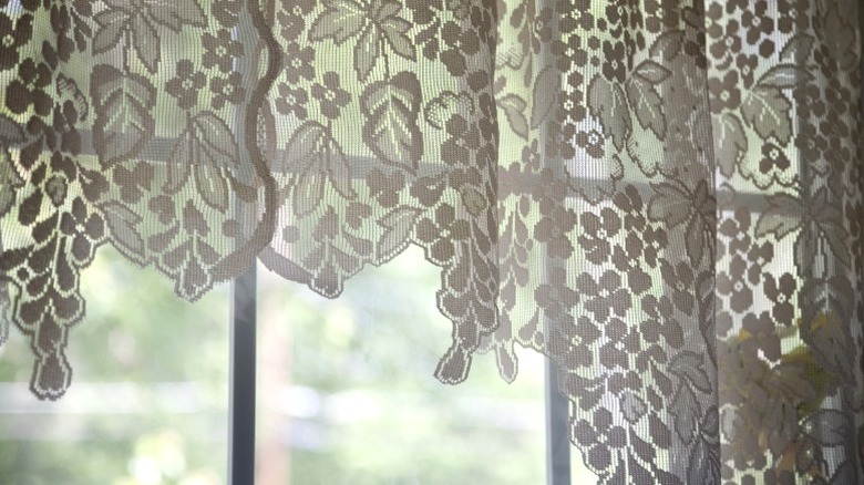 Lace curtains with floral pattern in front of a kitchen window