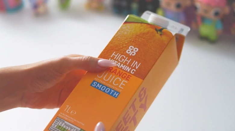 person holding orange juice carton