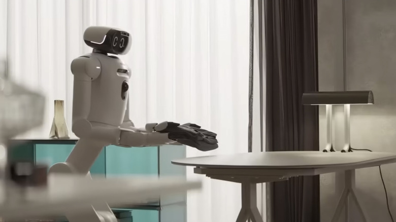 An LG CLOiD robot carries a folded shirt to a white table