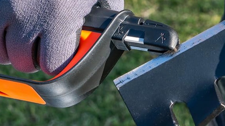 Worker wearing gloves sharpening lawn mower blade with a Sharpal tool