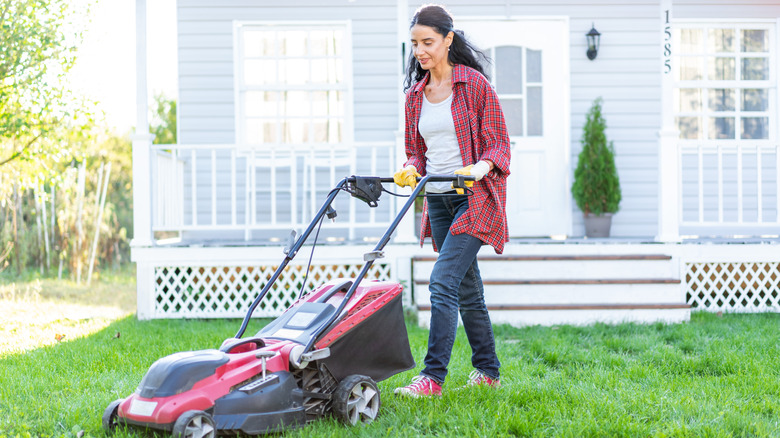 Woman mowing lawn with a modern, rotary push mower.