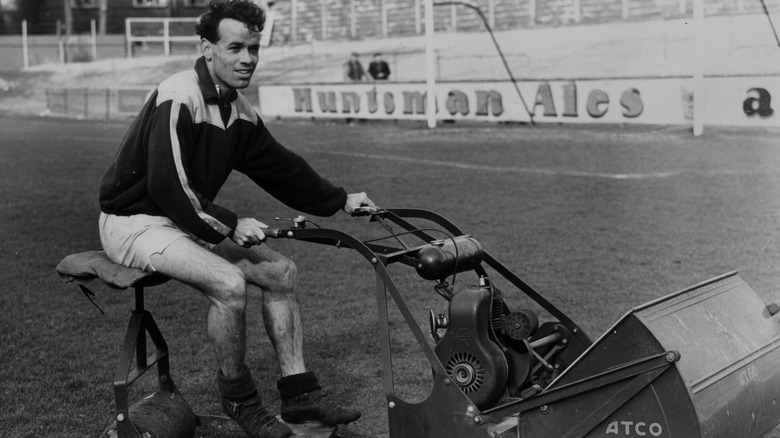 Man using an early gas-powered riding mowers.