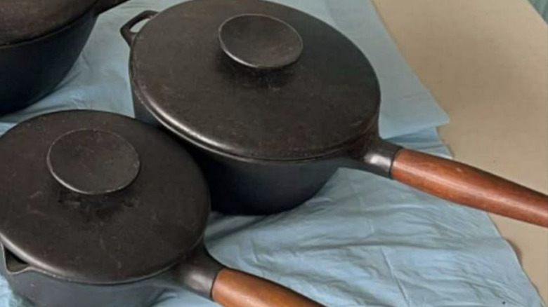 Two black pots with wooden handles.