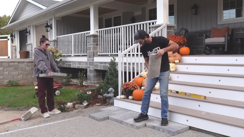 A homeowner couple DIY building an interlocking paver walkway in front of their home