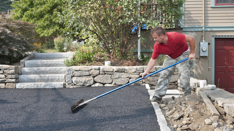 A man smoothing out an asphalt driveway