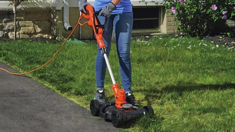 A person using the BLACK+DECKER Corded Electric Lawn Mower on grass
