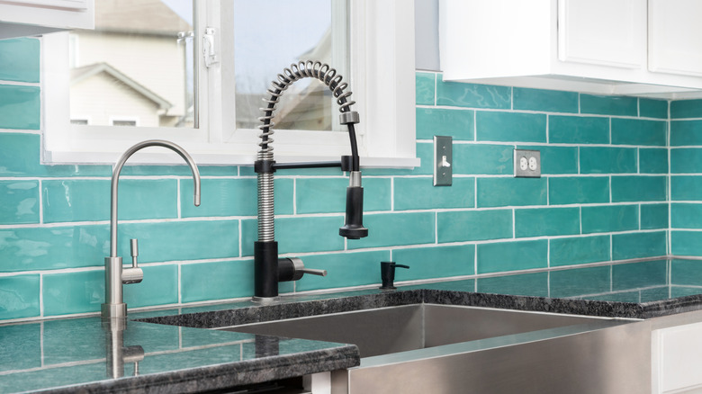 A kitchen sink in front of robin's egg blue subway tile backsplash