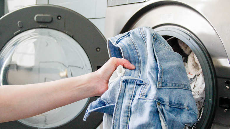 a hand loading a washer with clothes