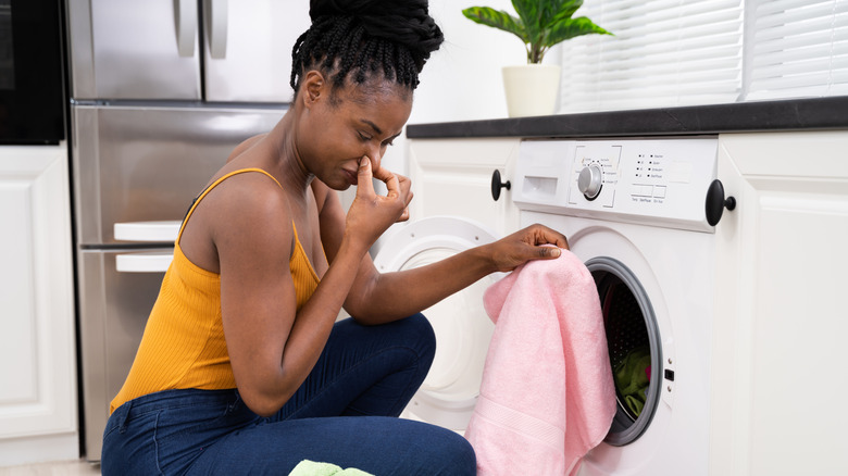 a woman taking laundry out of a smelly washer