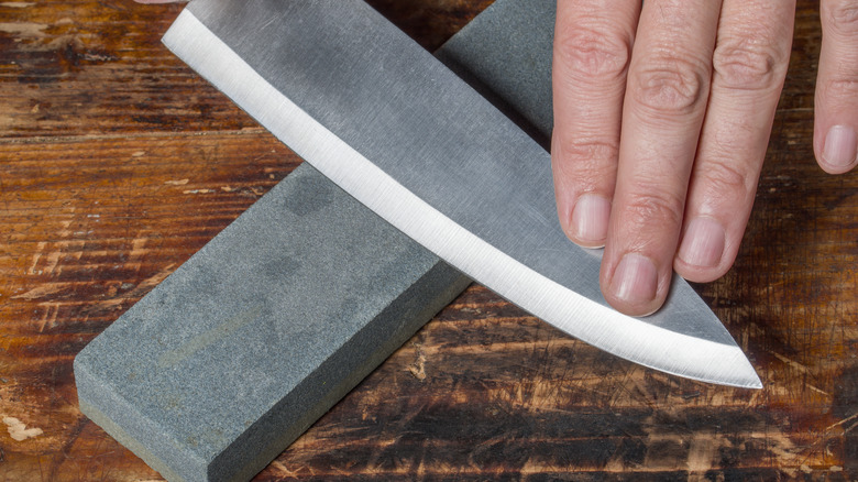 using a stone to sharpen a knife