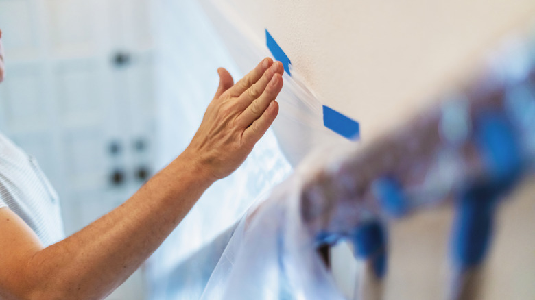 Woman marking up walls with blue painter's tape