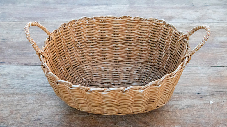 Woven basket with handles placed on wooden surface