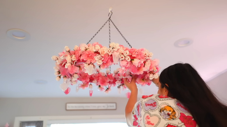 A floral-covered chandelier illuminates a feminine pink room