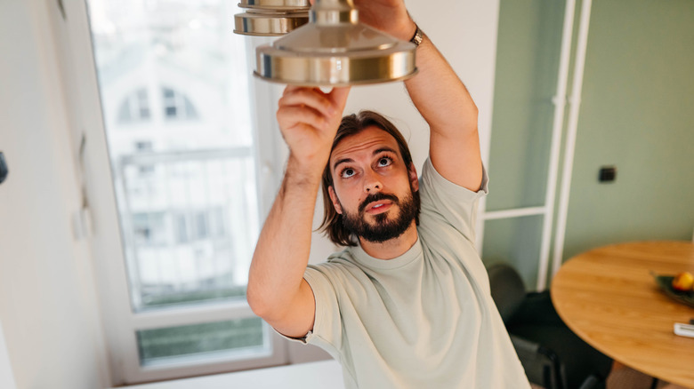 a man changes a ceiling lightbulb