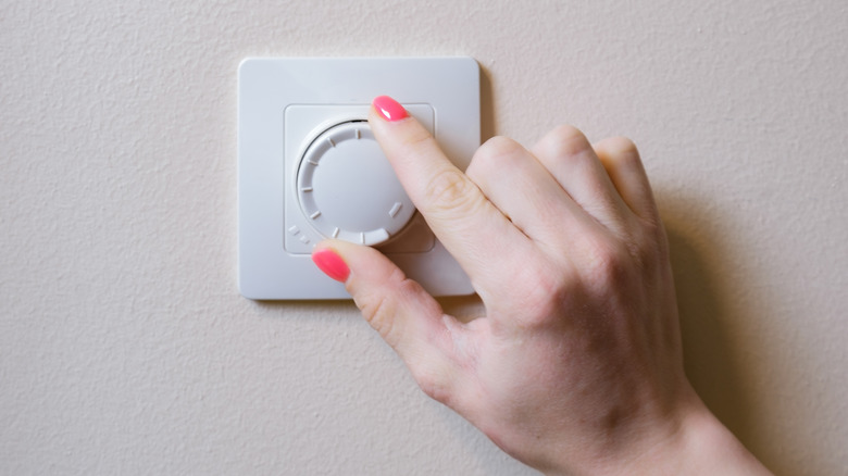 a woman adjusts a light dimmer switch