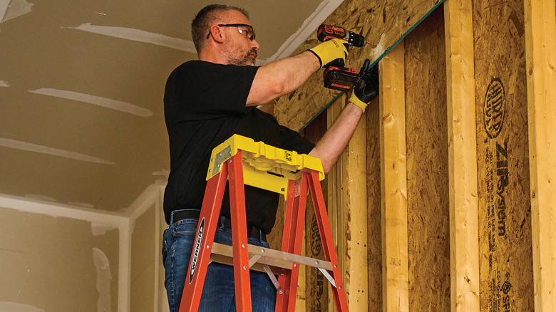 A man standing on a Werner 6-foot fiberglass ladder.