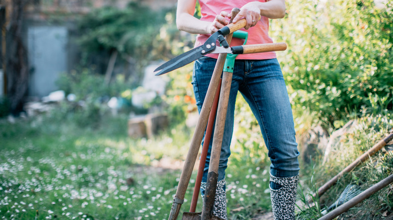 Woman holding gardening equipment in her garden