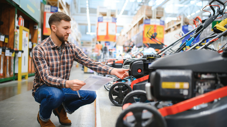 Young man shopping for lawn mowers.