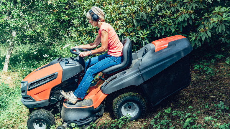 Woman driving a riding lawn mower.