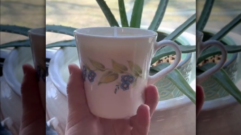 A hand holds a coffee cup that's been turned into a candle