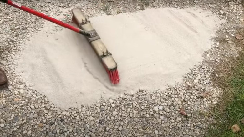 spreading cement powder on a gravel driveway