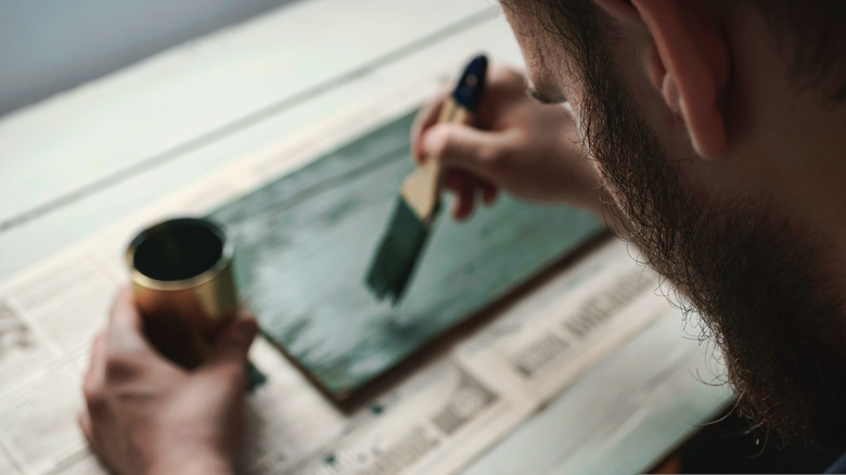 An overhead shot of a man painting a small board