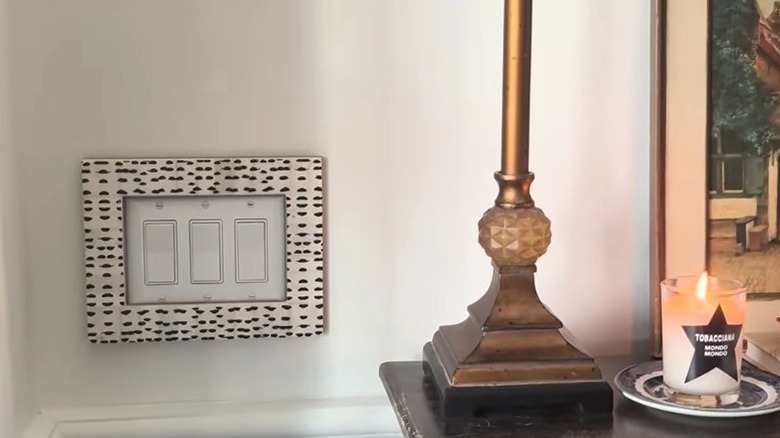 stylish picture frame positioned around a three-gang light switch