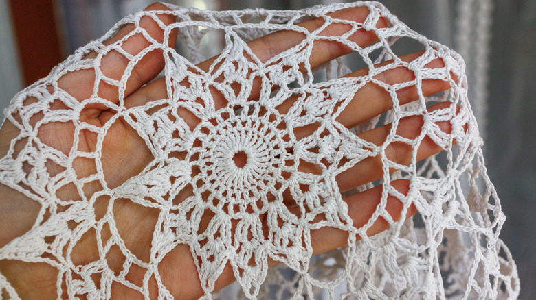 A white doily in a woman's hand