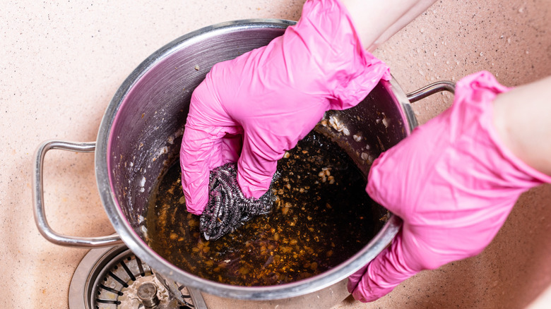 Person scrubbing burnt pot in the sink