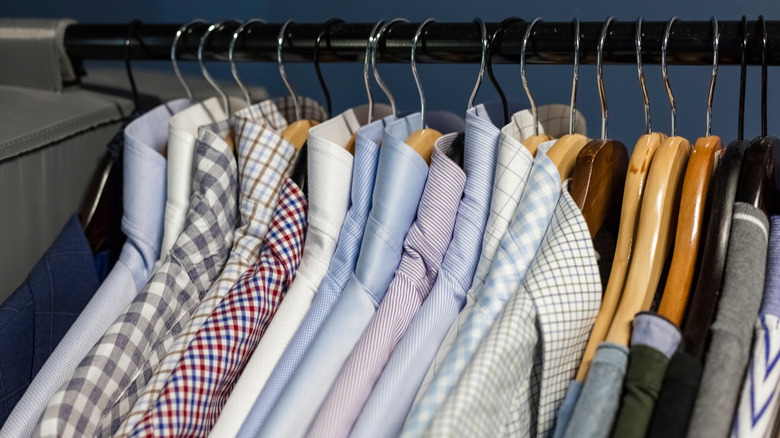 Men's pressed button-down shirts hanging in closet