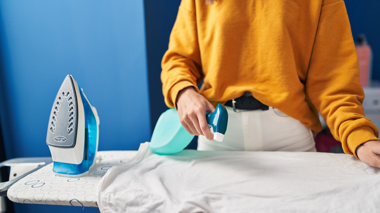 Woman spraying shirt with starching solution