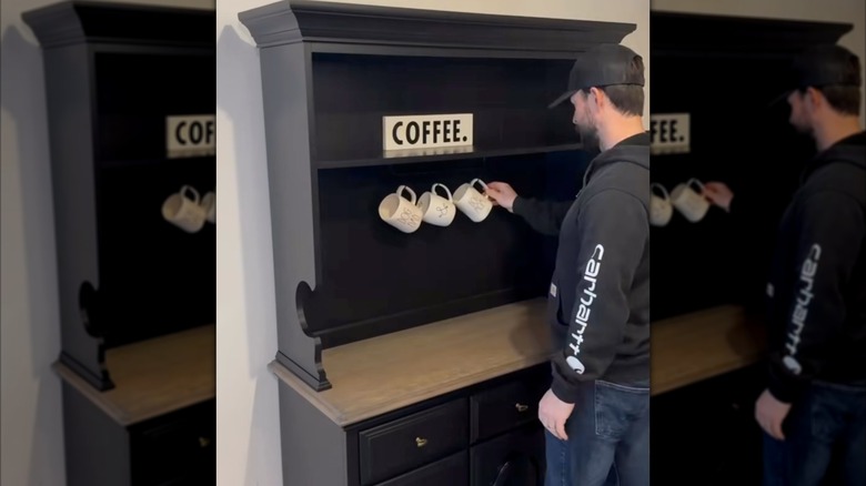 man hanging mugs in coffee station