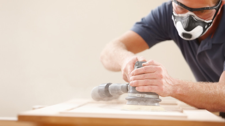 A man sands an old hutch