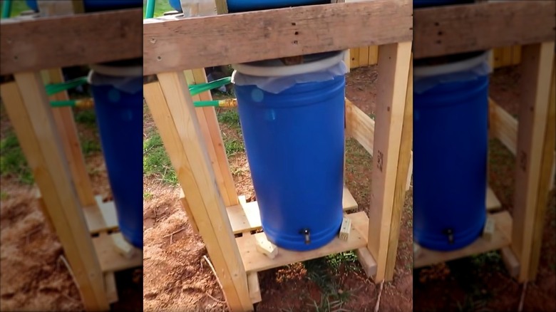 A rain barrel stand with two layers and two rain barrels connected by a tube