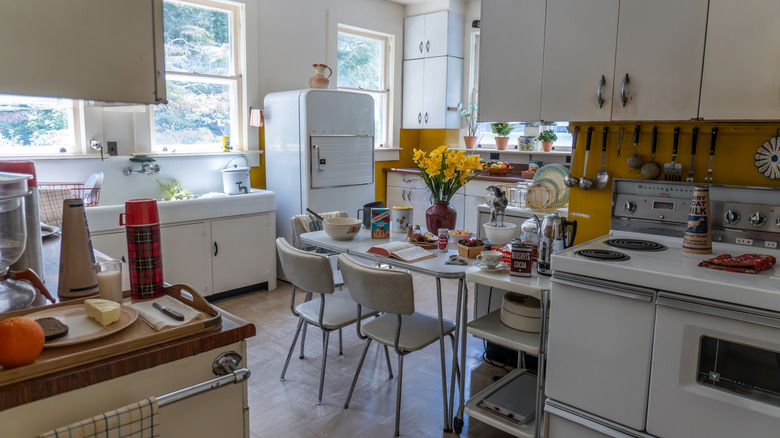 A retro kitchen from the 1960s with white cabinets and yellow tile