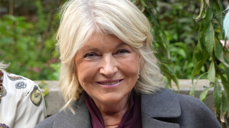 Martha Stewart posing in front of greenery