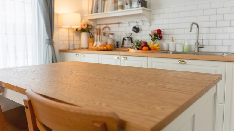 Beautiful wooden countertop over white kitchen cabinets and an island