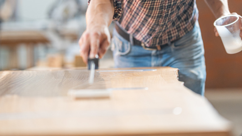 Man applying epoxy resin to a live-edge wooden countertop