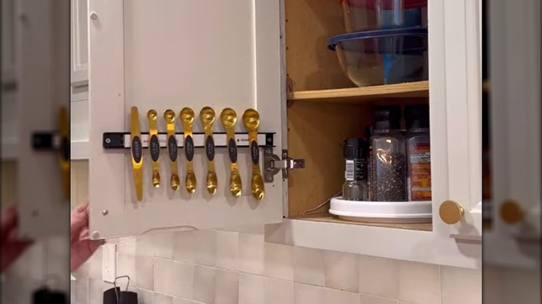 Gold metal measuring spoons hanging on magnetic knife rack