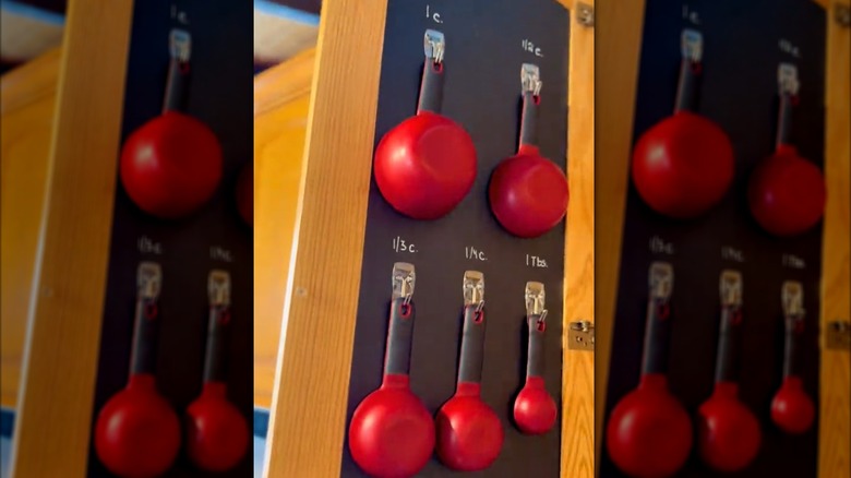 Hanging red measuring cup set on DIY chalkboard-style organizer inside cabinet