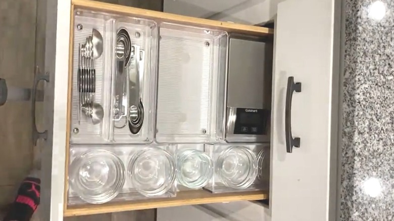 Metal measuring spoons and cups divided by plastic bins in kitchen drawer