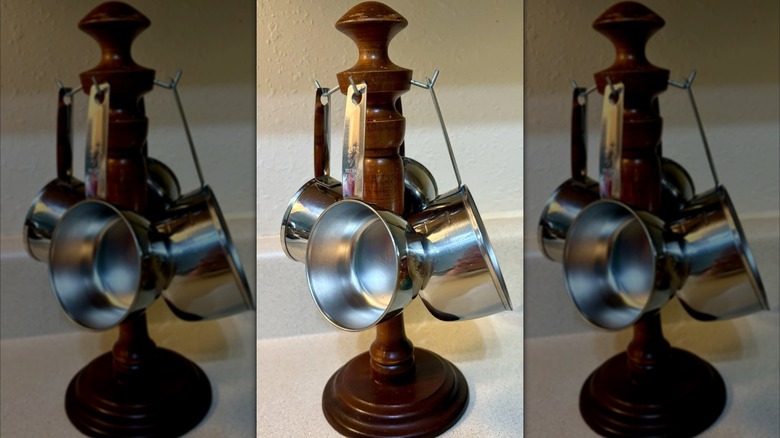 Vintage measuring spoon rack with hanging metal instruments on white countertop