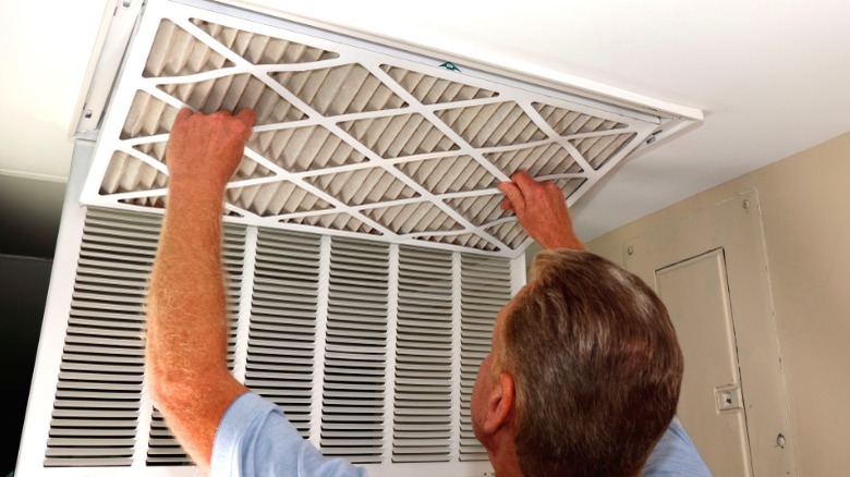 Man changing HVAC air filter in ceiling