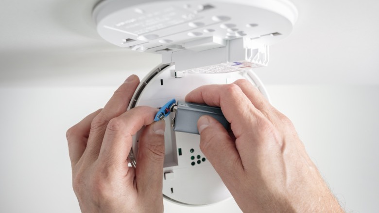 Person changing a smoke detector battery