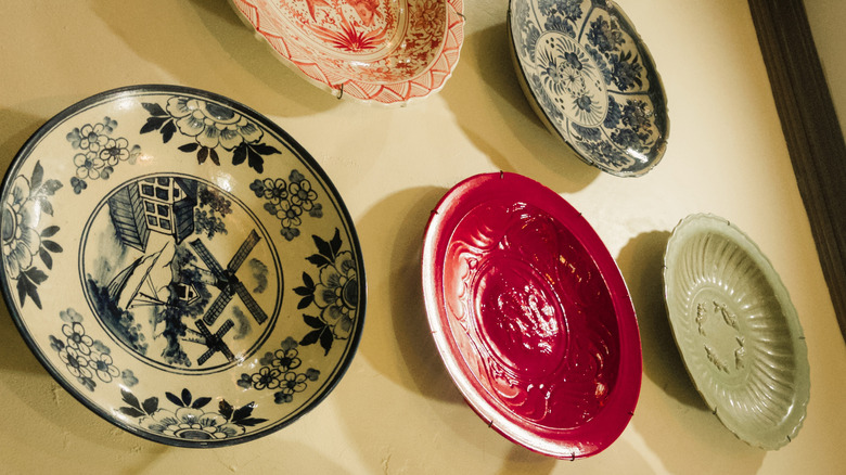 Blue, red, and beige vintage plates hanging on an off-white wall