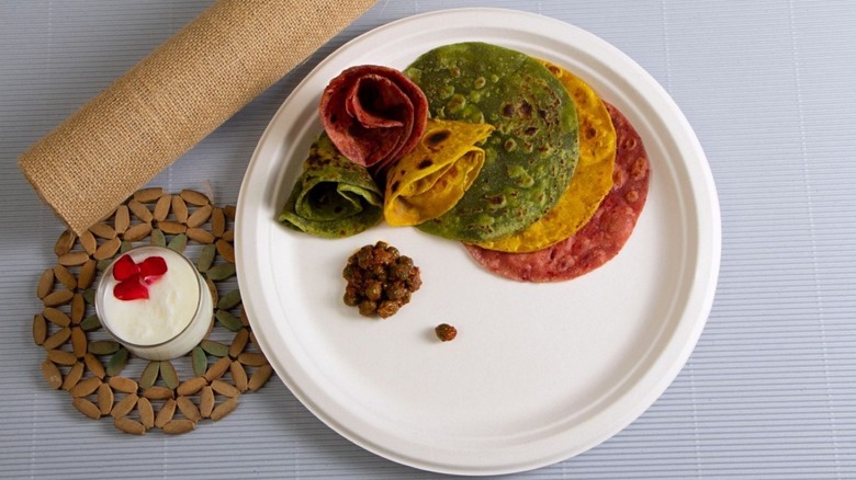 Bagasse plate full of food sitting beside a placemat and a drink