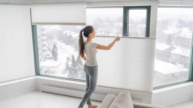 A woman operating top-down bottom-up shades in a white minimalist room