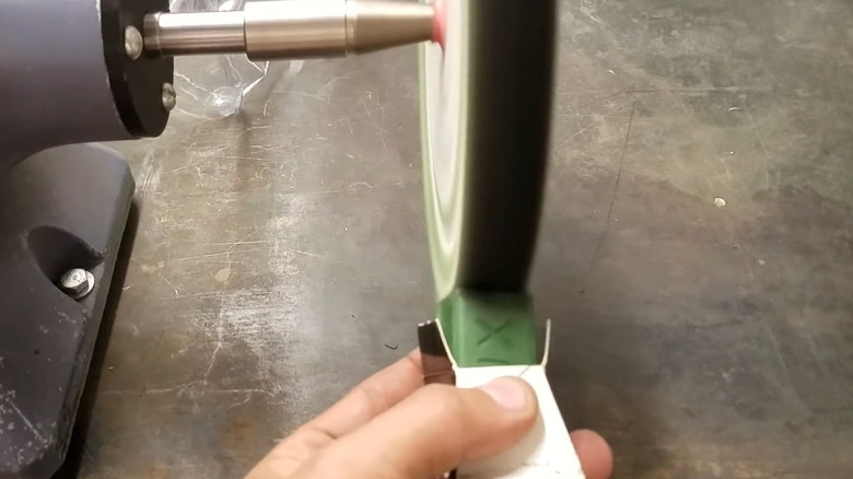 Adding polishing compound to a polishing pad on a bench grinder