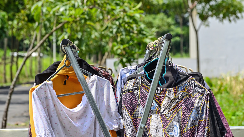 Colorful clothing dries on a clothesline in the yard outside in the sunlight.